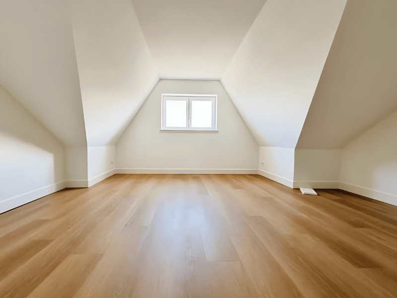 Lege zolder met houten vloer en raam