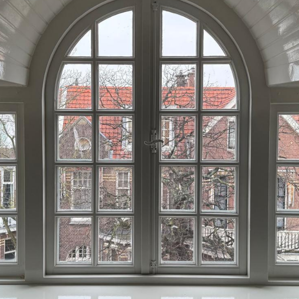 Grote raam met uitzicht op bakstenen huizen.